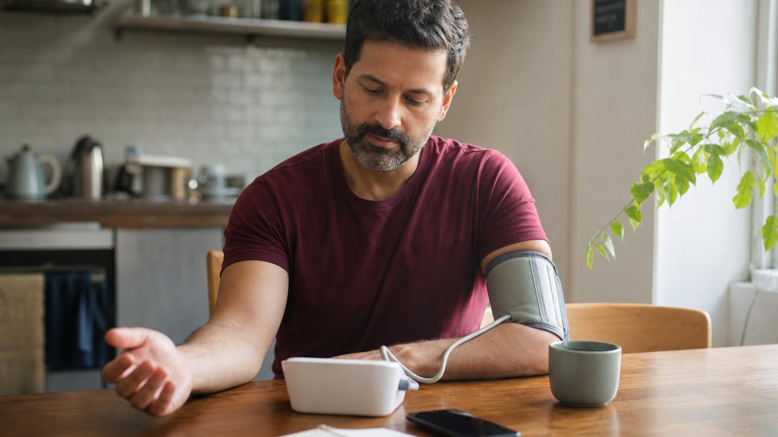 A home blood pressure monitor set up on a bright bedside table for a routine reading